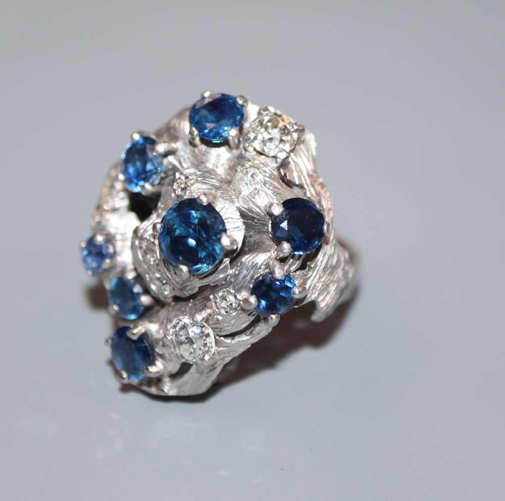 A 1970s? textured 18ct, sapphire and diamond cluster dress ring, in a raised setting, size P, gross 14.7 grams.